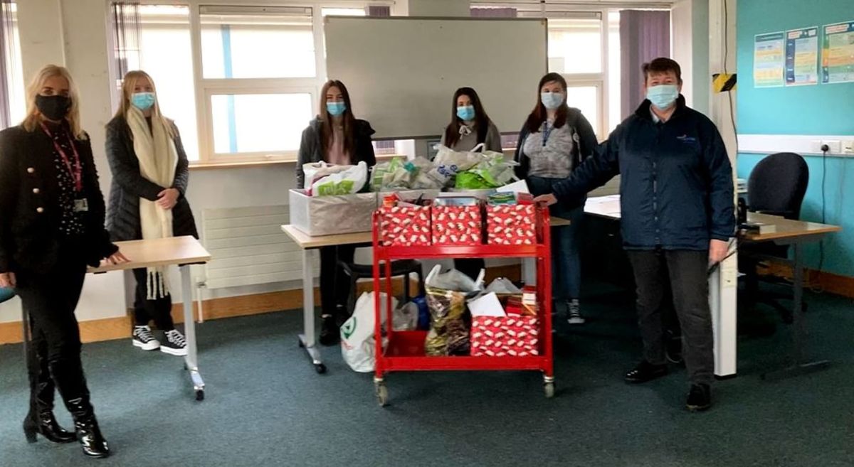 Staff and students in class room with trolly filled with hampers.